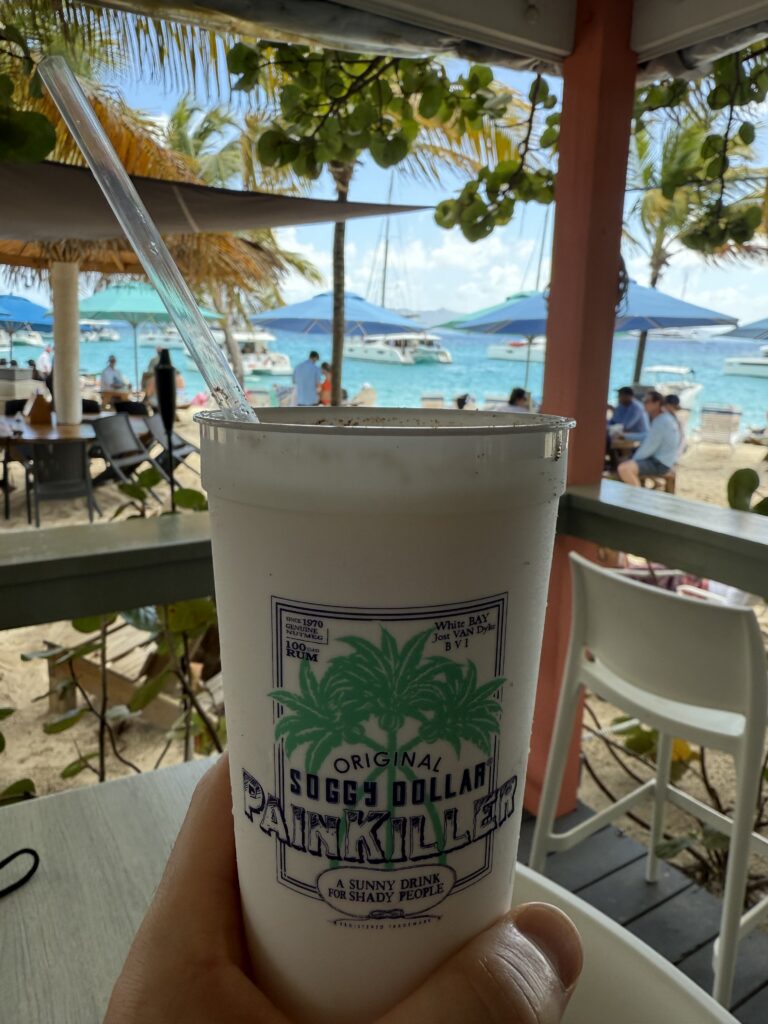 A Painkiller cocktail from the Soggy Dollar Bar, with White Bay in the background